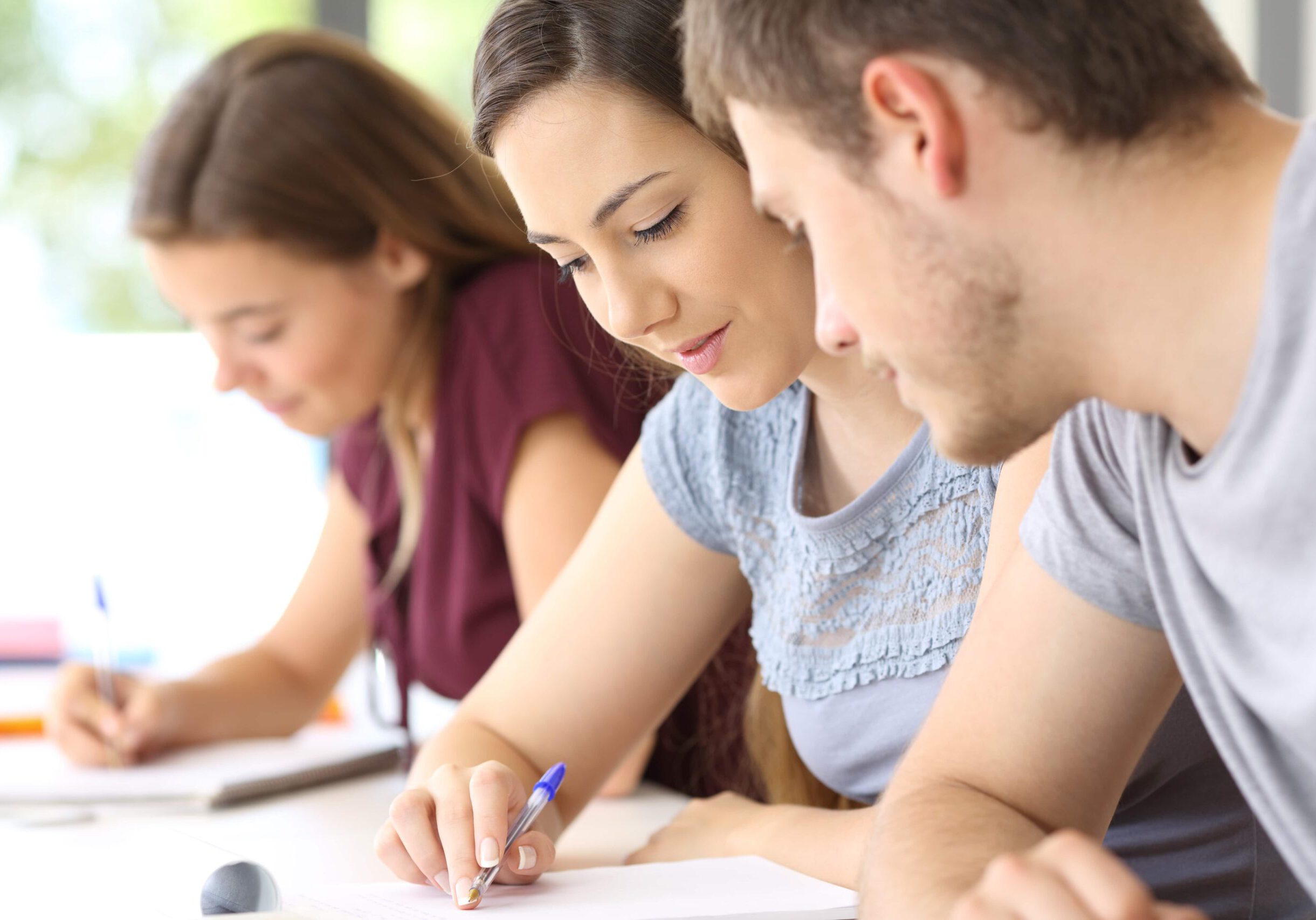 Student helping to a classmate in classroom with other girl in the background